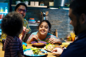 Family of four eating dinner tother.