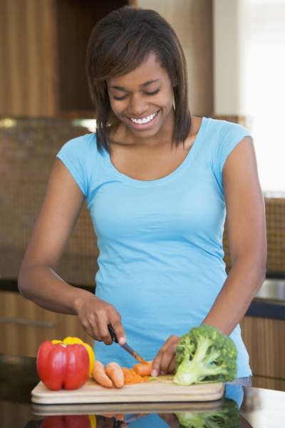 Young woman smiling and cutting some vegetables